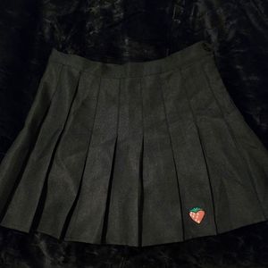 Black pleated skirt with a strawberry logo on front with shorts attached inside.